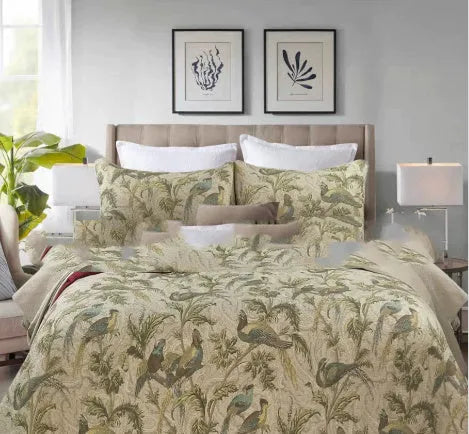 Blue American-style floral and bird quilted cotton bedspread set on a bed, showing textured stitching.