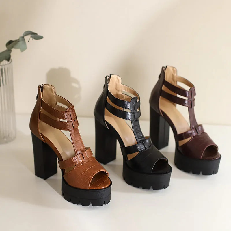 Black platform high heel sandals with a round toe and back zipper on a wooden floor.