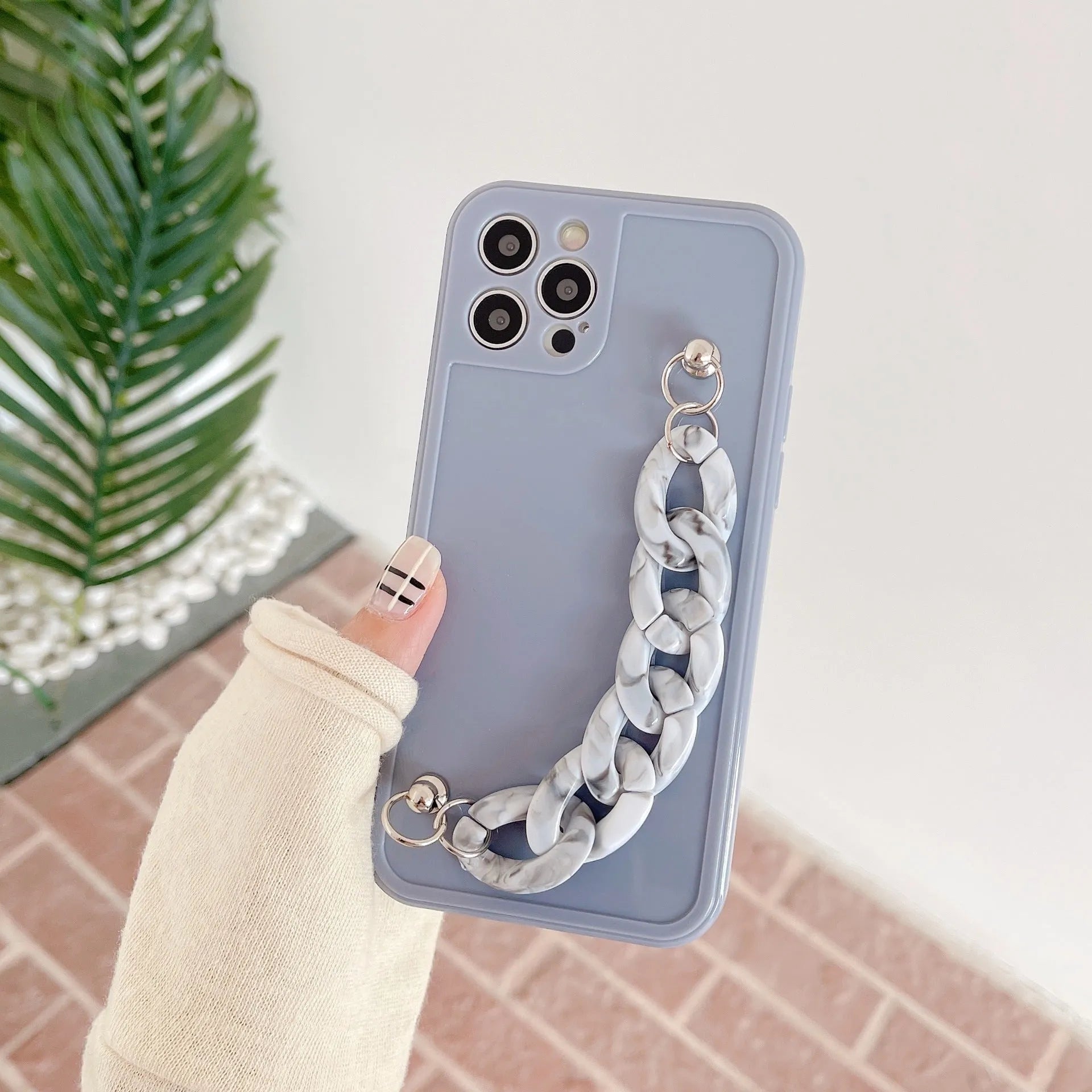 Marbled silicone phone case for iPhone with side lanyard hole in antique white, grey blue, and transparent coffee colours.