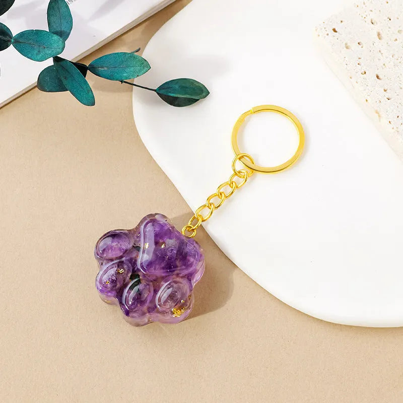 Hand-finished natural crystal cat's paw keychain pendant on a metal ring, showing detailed carving and polished stone surface.
