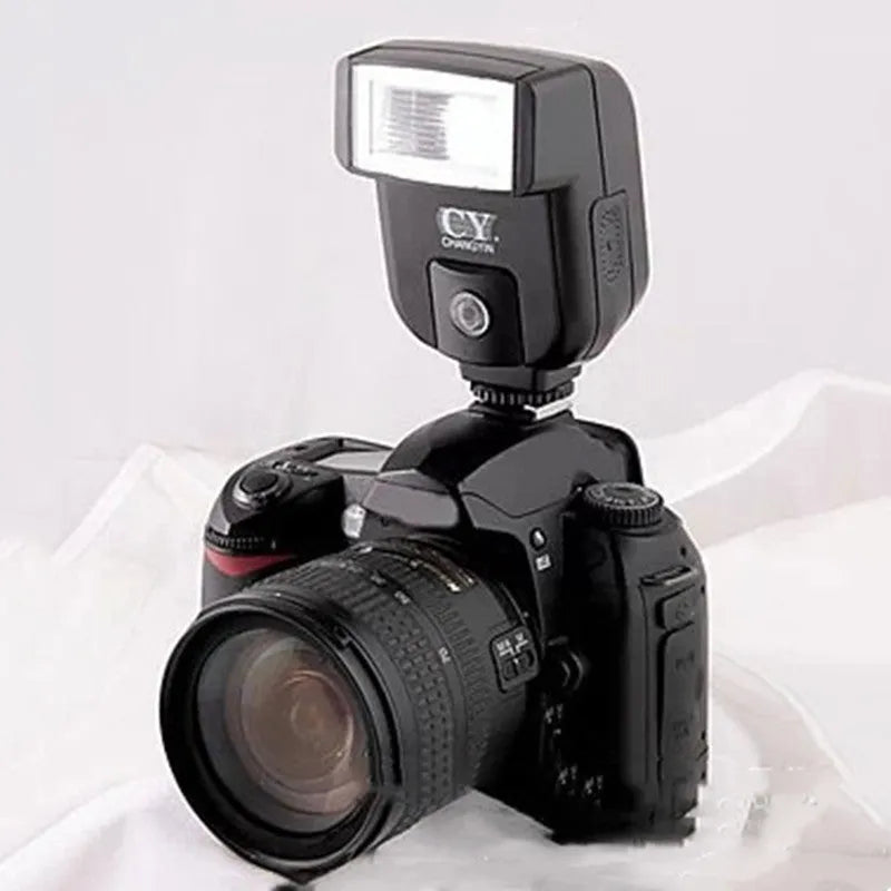Compact silver hot shoe camera flash unit with head tilted upwards, shown on a camera.