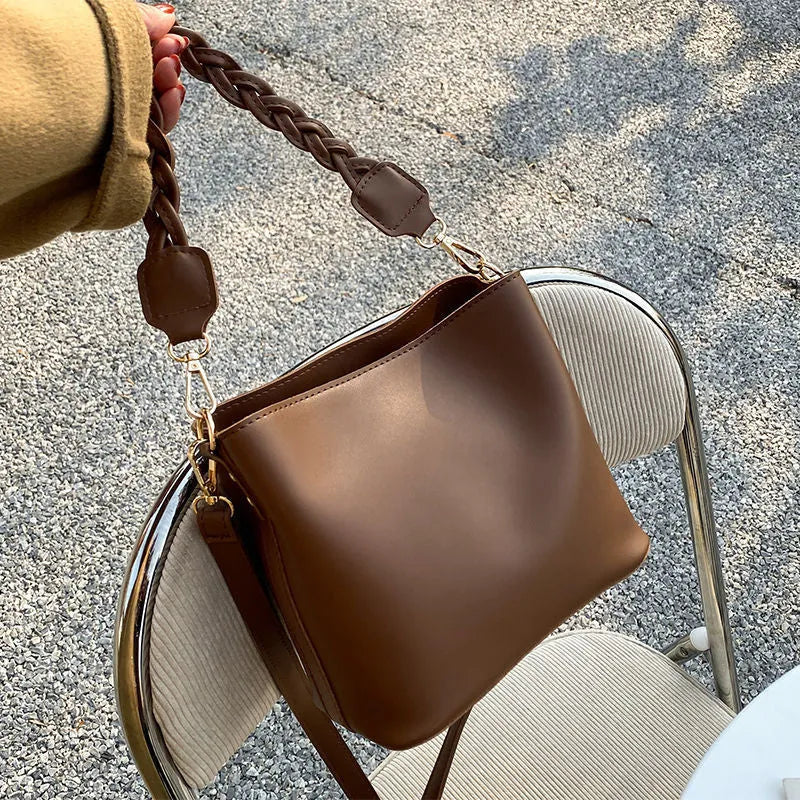 Retro style khaki crossbody bucket bag with weaving detail on the front.