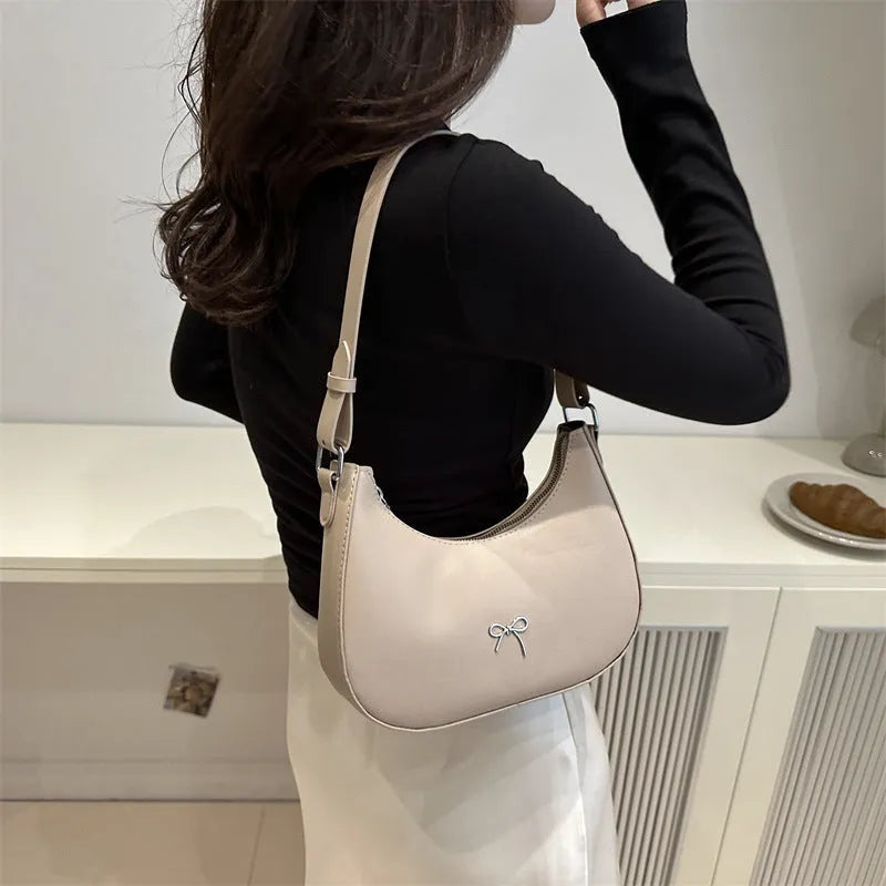 Women's black dumpling-shaped PU shoulder baguette handbag with a single strap and sewing thread detail.
