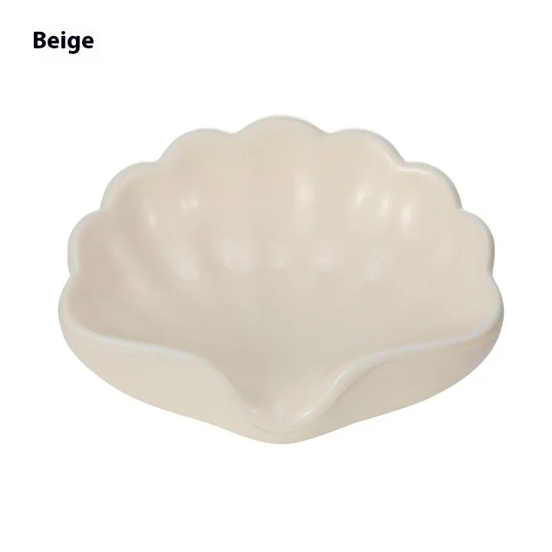 White or pink plastic shell-shaped soap dish for bathroom sink or shower.