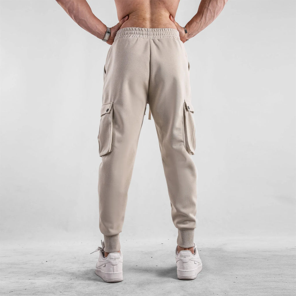 Men's loose-fit apricot coloured cotton sports trousers with an ankle tie and side pockets on a neutral background.
