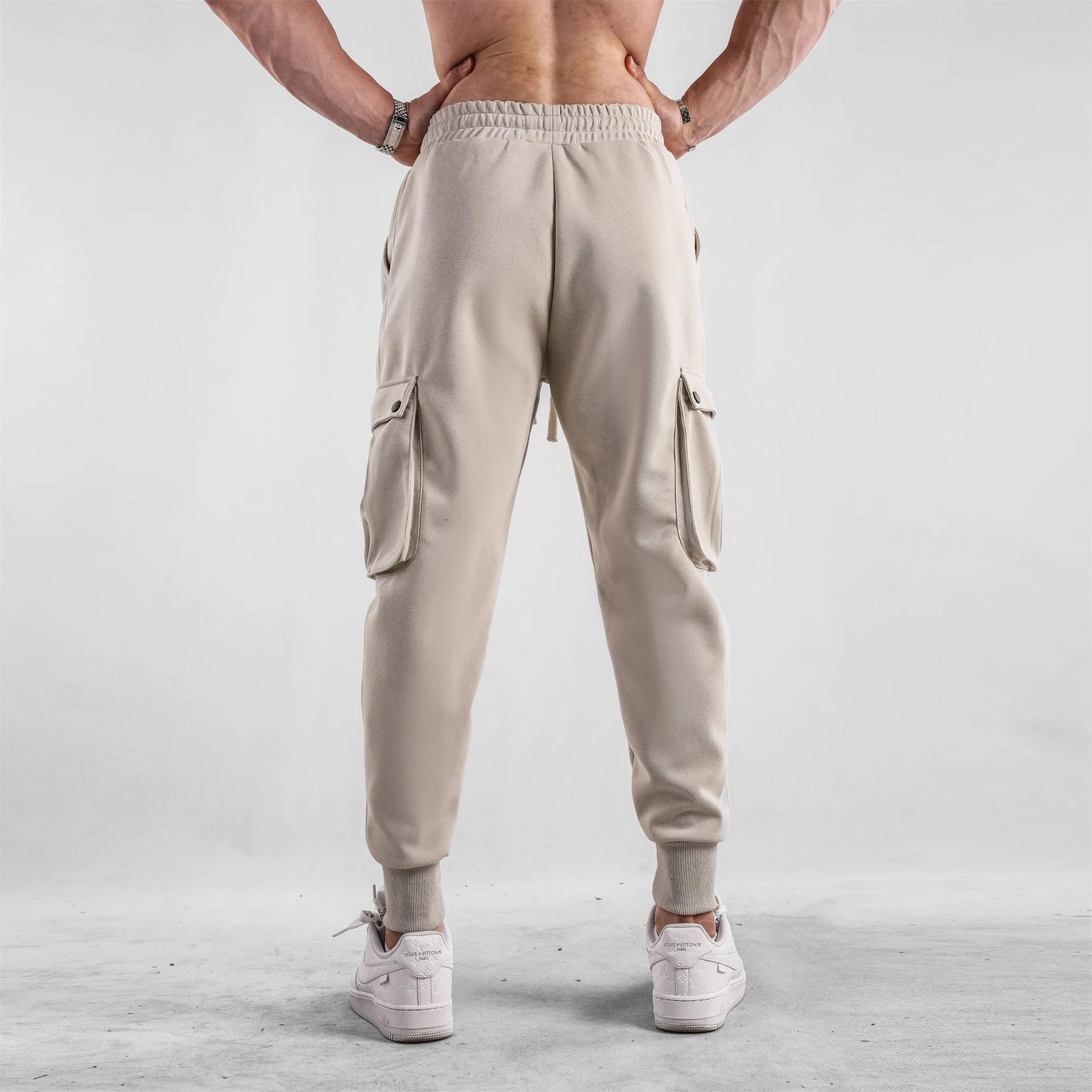 Men's loose-fit apricot coloured cotton sports trousers with an ankle tie and side pockets on a neutral background.