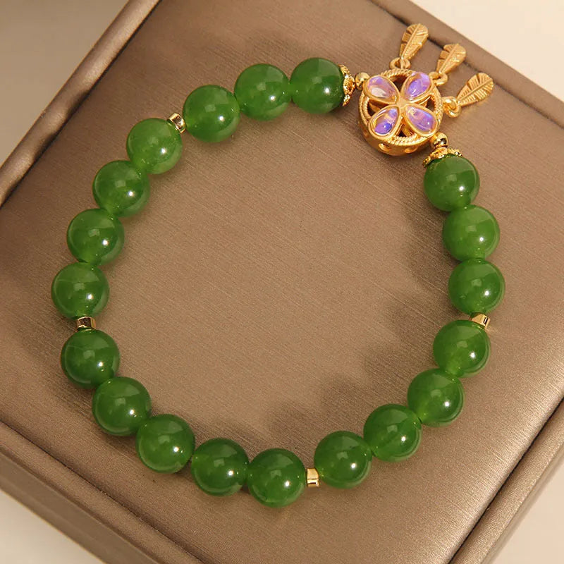 Green Jasper crystal bracelet with a four-leaf clover dream catcher pendant on a woman's wrist.