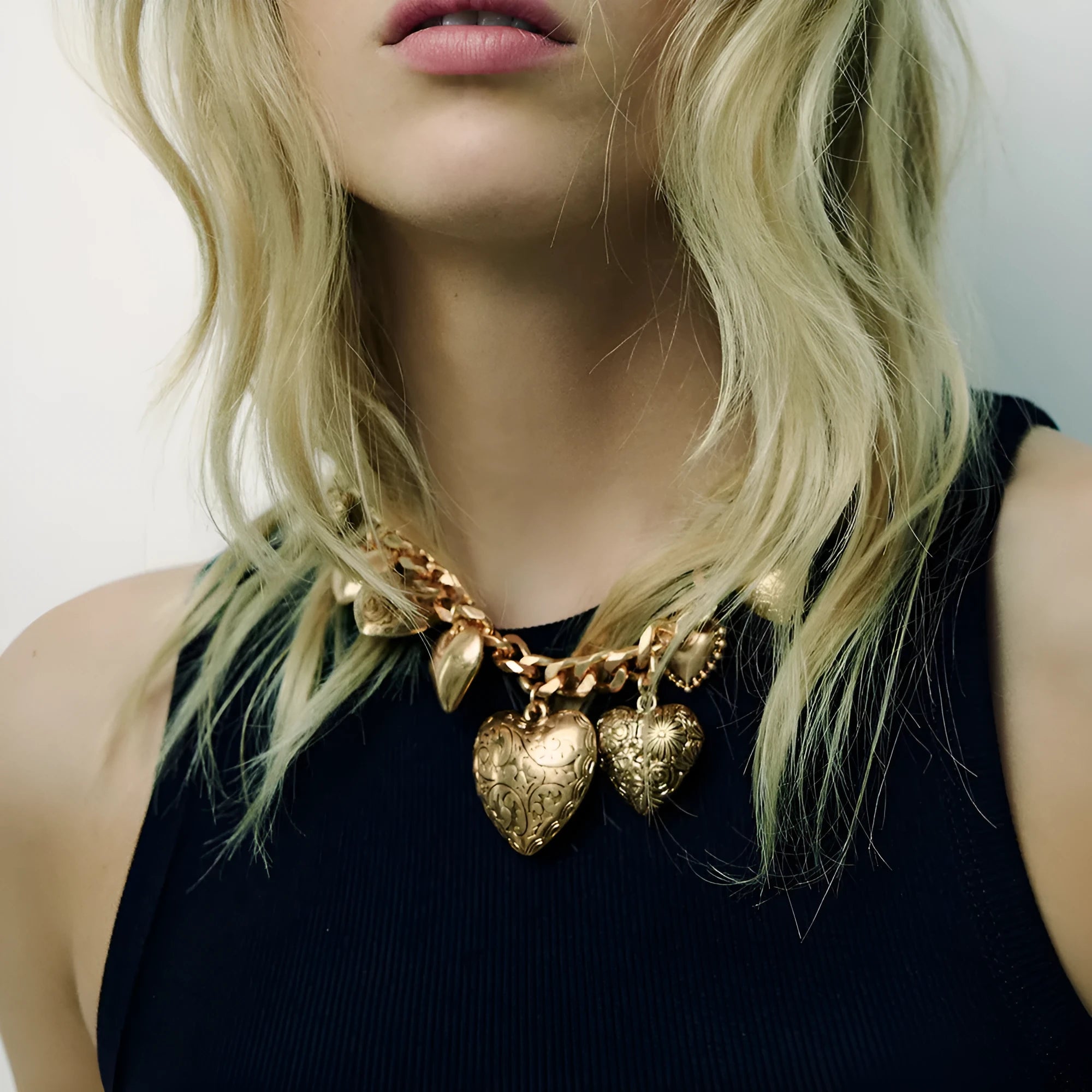 Gold exaggerated carved heart pendant necklace on model, showing adjustable metal chain.