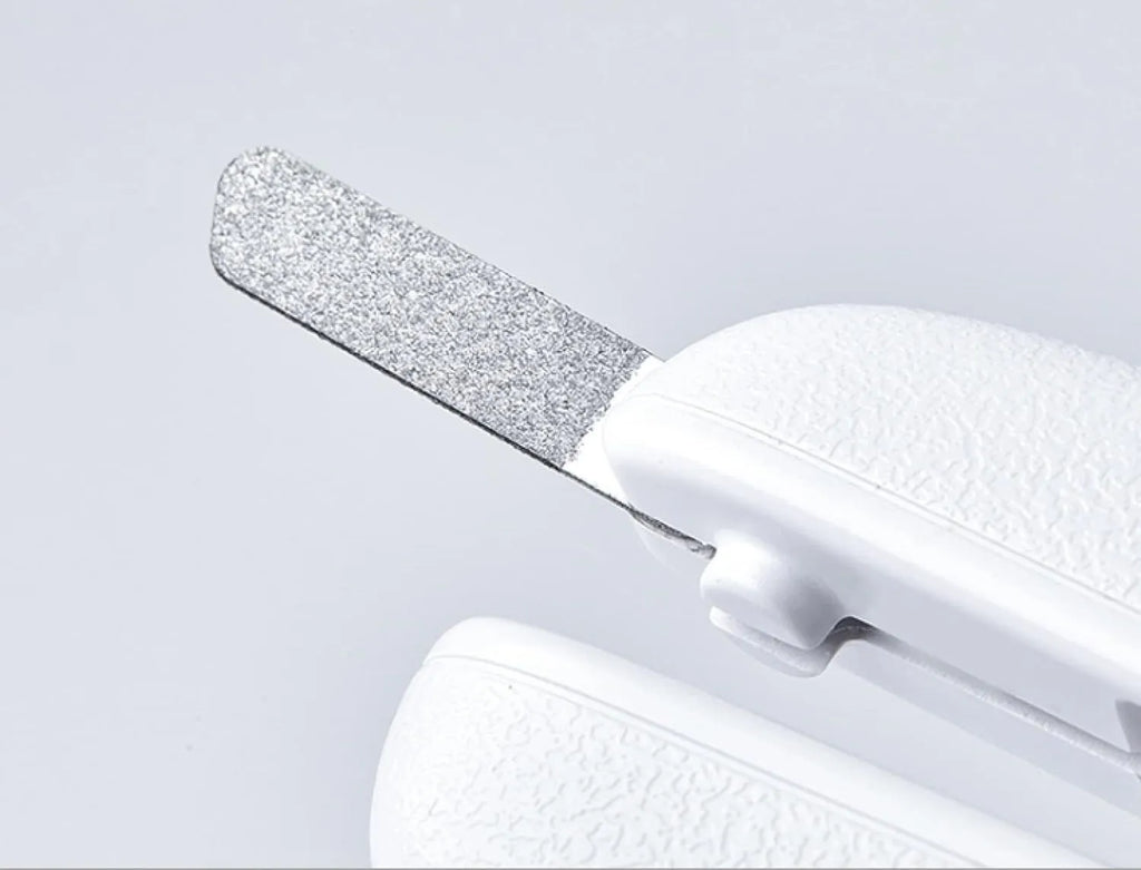 White pet nail clippers with LED light and transparent anti-splash guard next to a nail file on a table