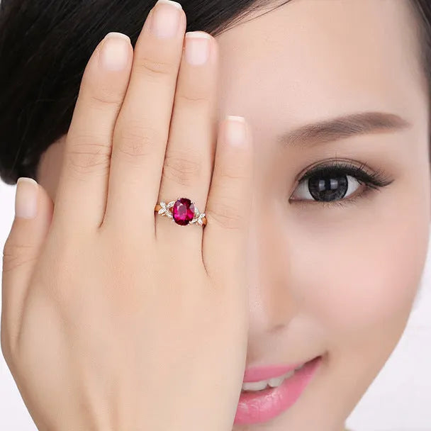 Women's butterfly-shaped ring with heart crystal in rose gold plating on blue or red background