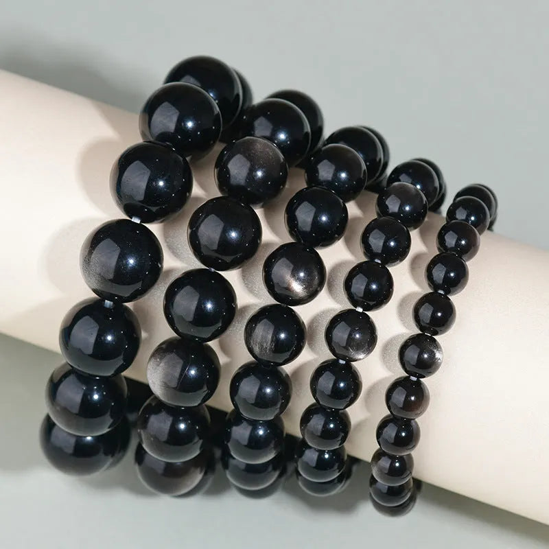 Hand-woven round obsidian bead bracelet on a wrist, showing ethnic style and multiple colour options.