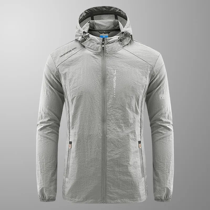 Man wearing a light grey loose-fit hooded nylon summer jacket outdoors.