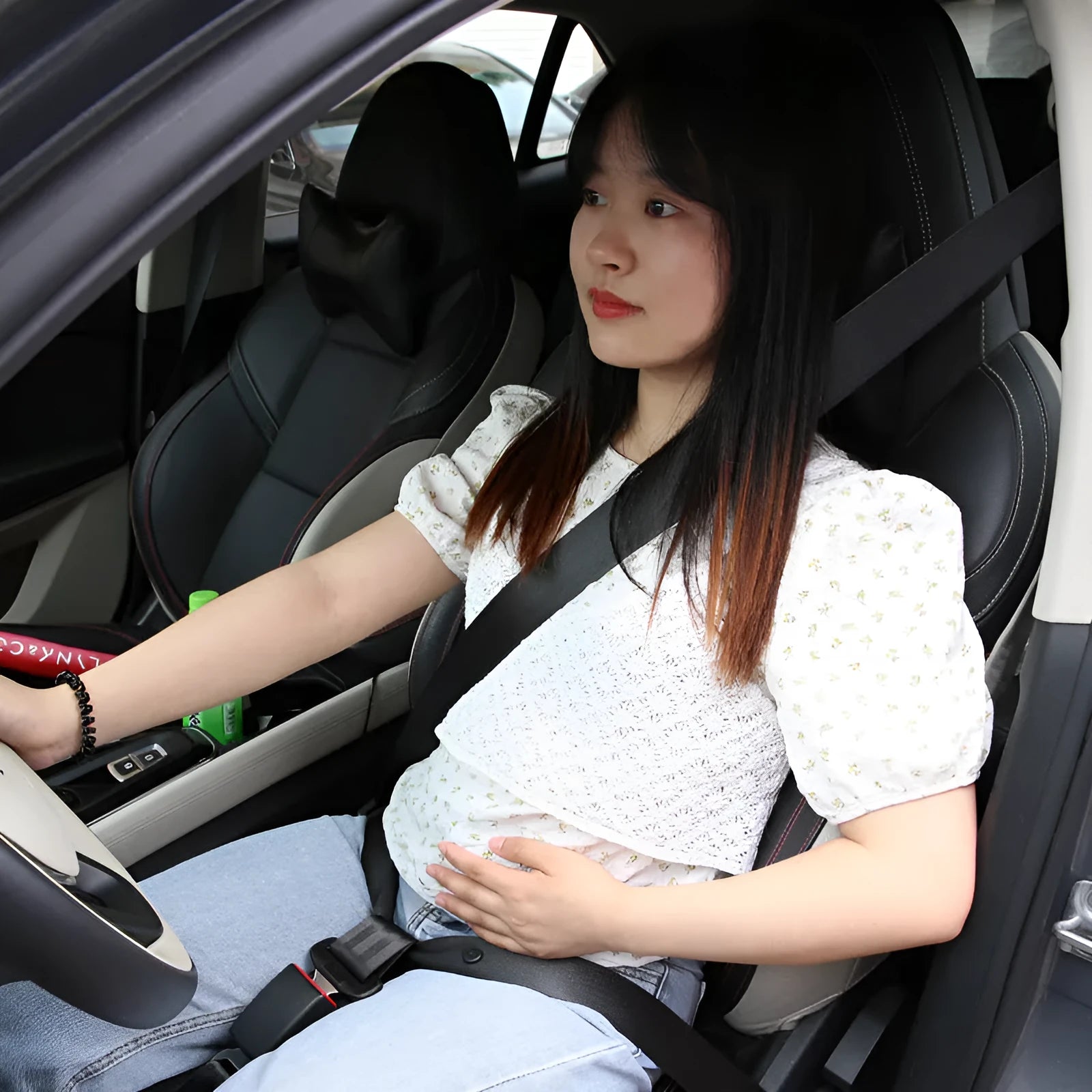 Adjustable black maternity car seat belt extension shown wrapped around a car seat.