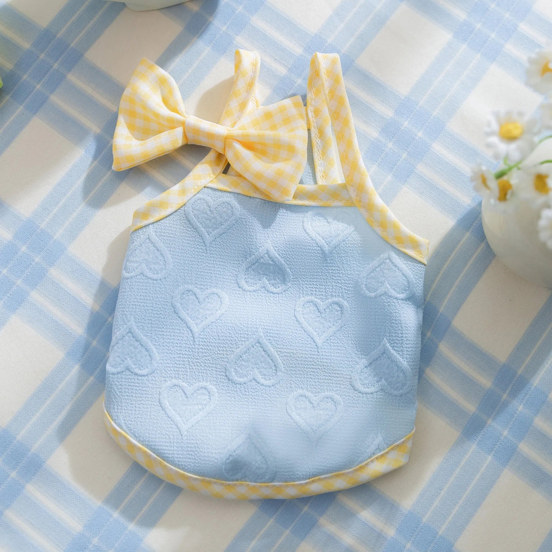 Small dog wearing a blue elastic vest with heart texture and bow suspenders.