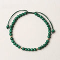 Natural green malachite crystal bracelet with golden balls on a woven hand strap.