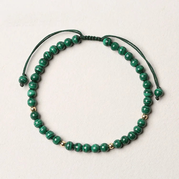 Natural green malachite crystal bracelet with golden balls on a woven hand strap.