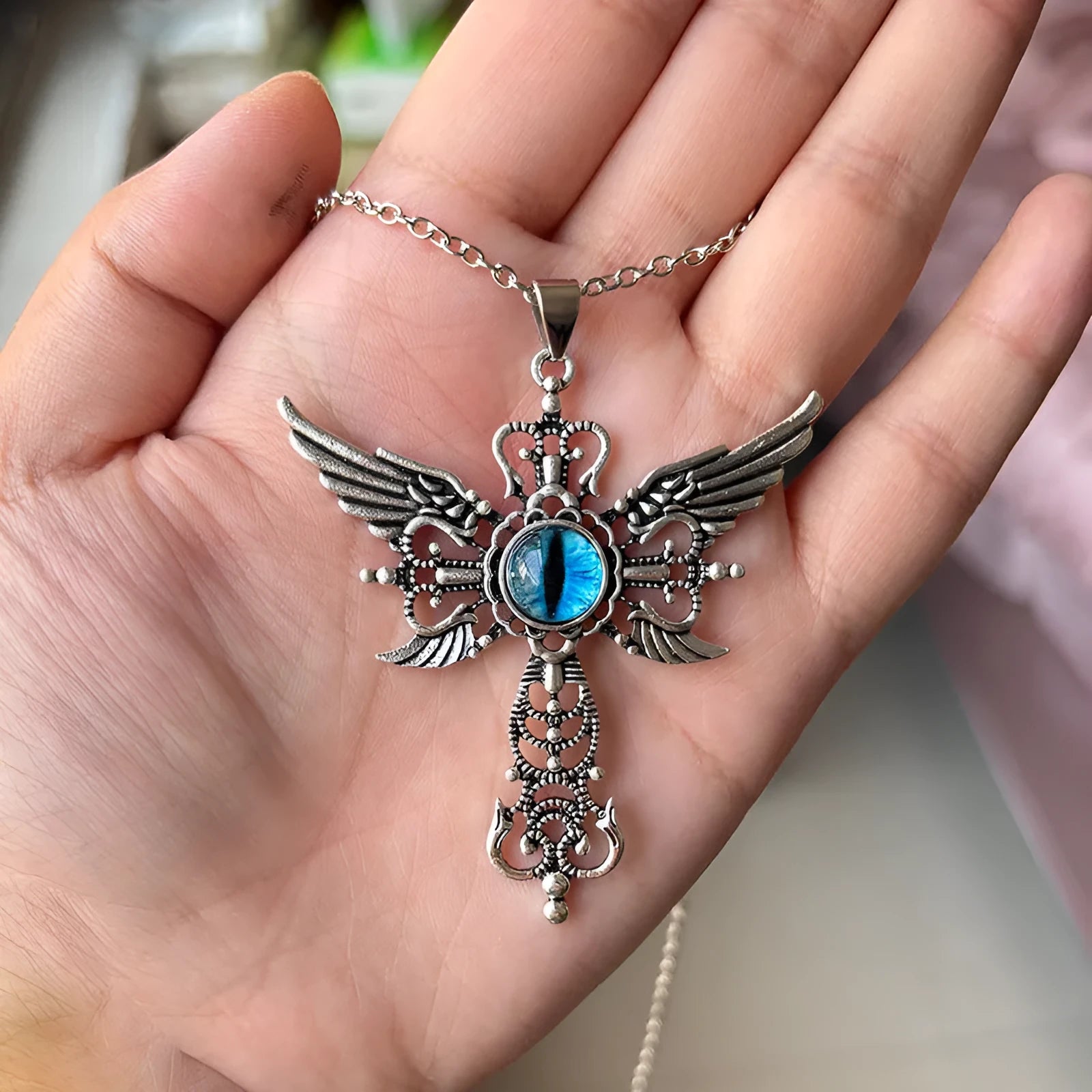 Geometric devil wings and cross alloy pendant necklace in blue on a silver chain.