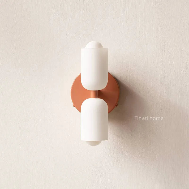 Cream base double head wall lamp with white glass shades against wall