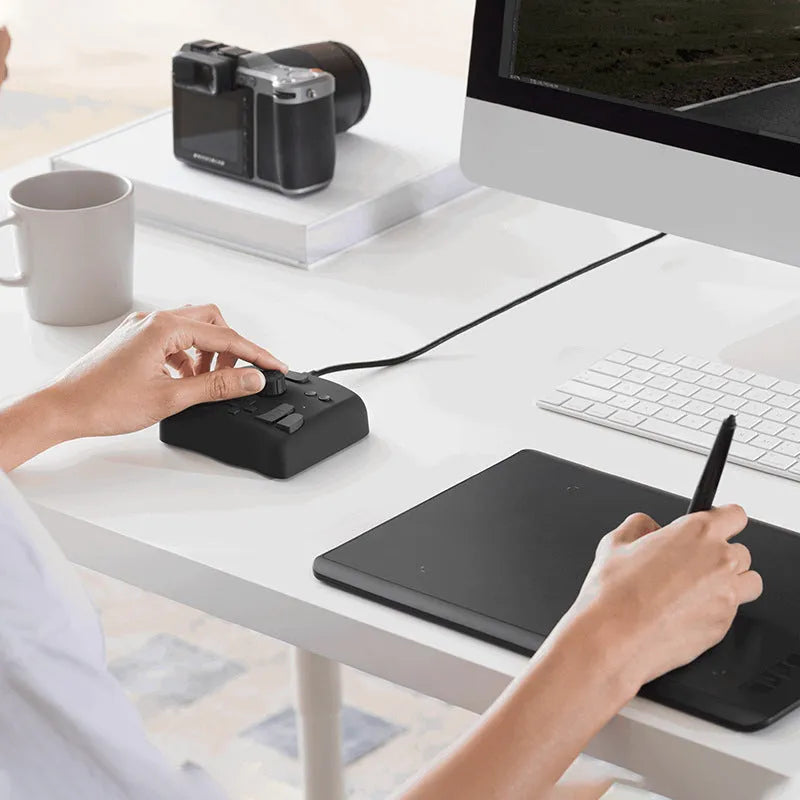 TourBox NEO black video editing controller with dials and buttons on a desk.