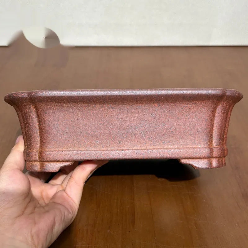 Reddish brown hand-glazed stoneware rectangular bonsai flower pot on a flat surface