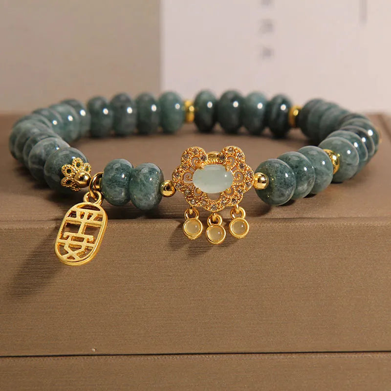 Close-up of a women's bracelet with green emerald jade and silver alloy abacus beads and a safety lock clasp.