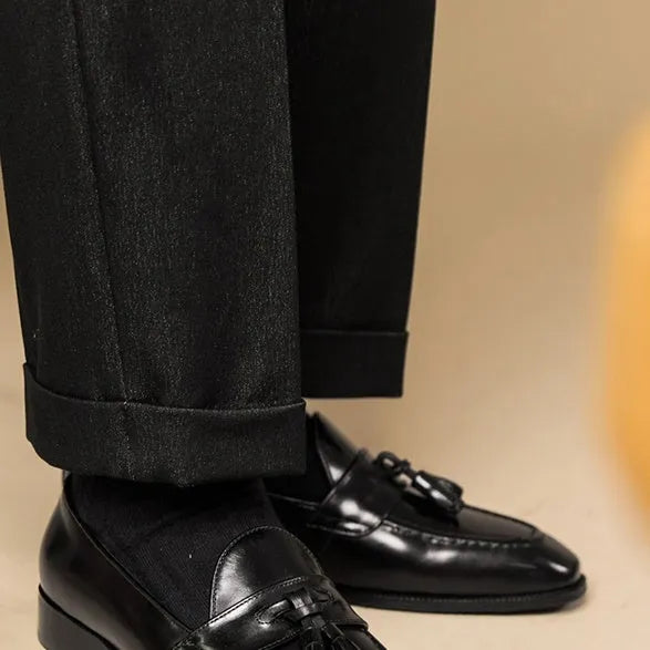 Men's black and brown polished leather tassel loafers for business casual wear, shown from the side.