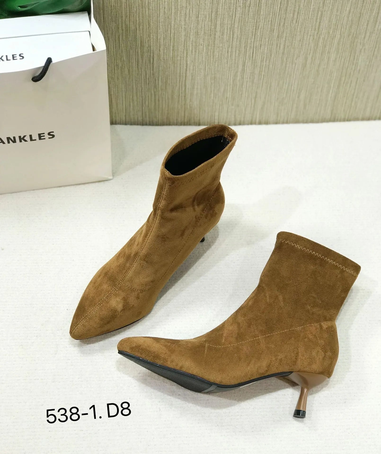 Black women's pointed toe ankle boots with a stiletto heel, shown on a foot.