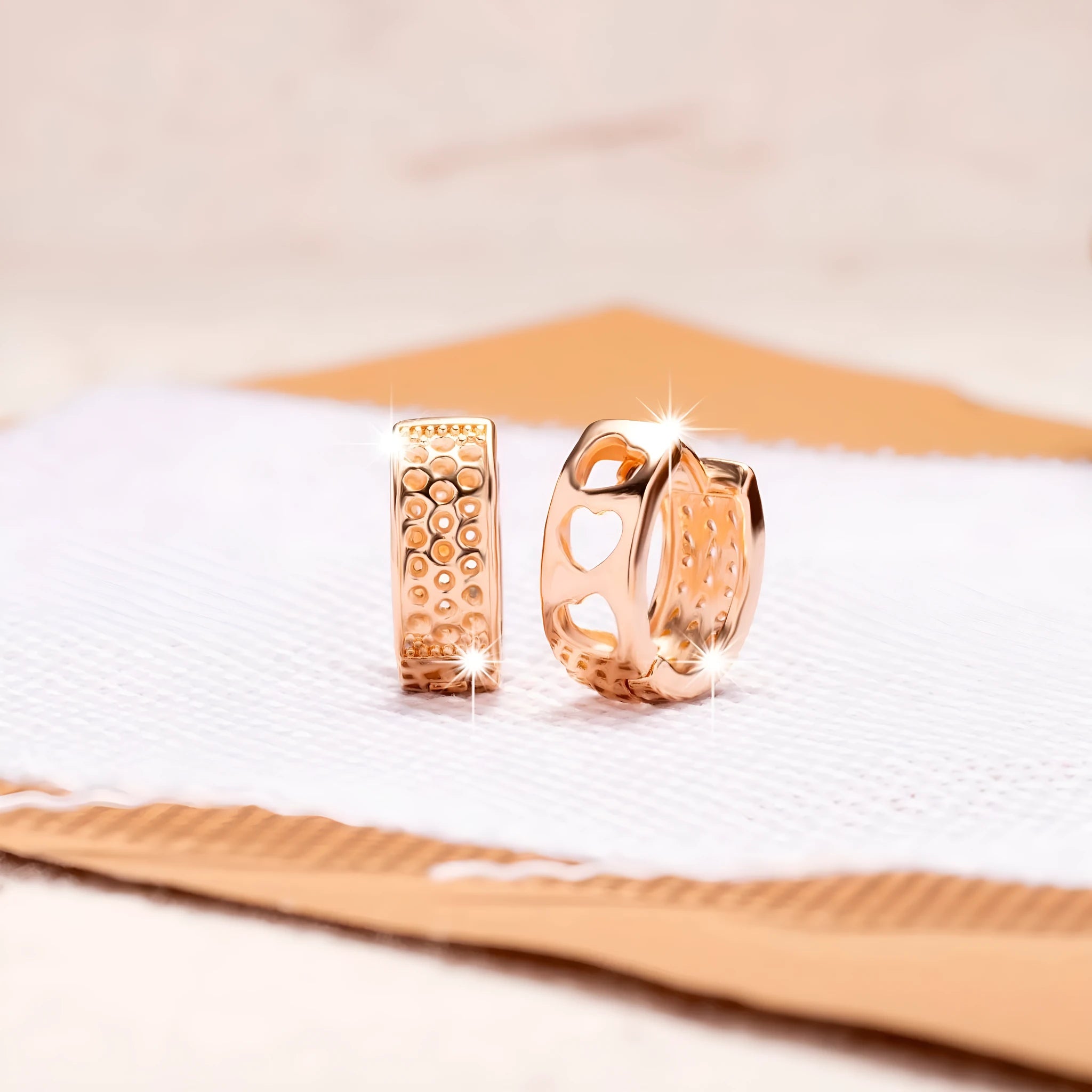 Rose gold circular earrings with a hollowed-out design showing three heart shapes.