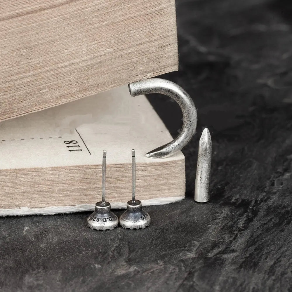 S925 sterling silver nail stud earrings in straight and curved punk designs on a plain background.
