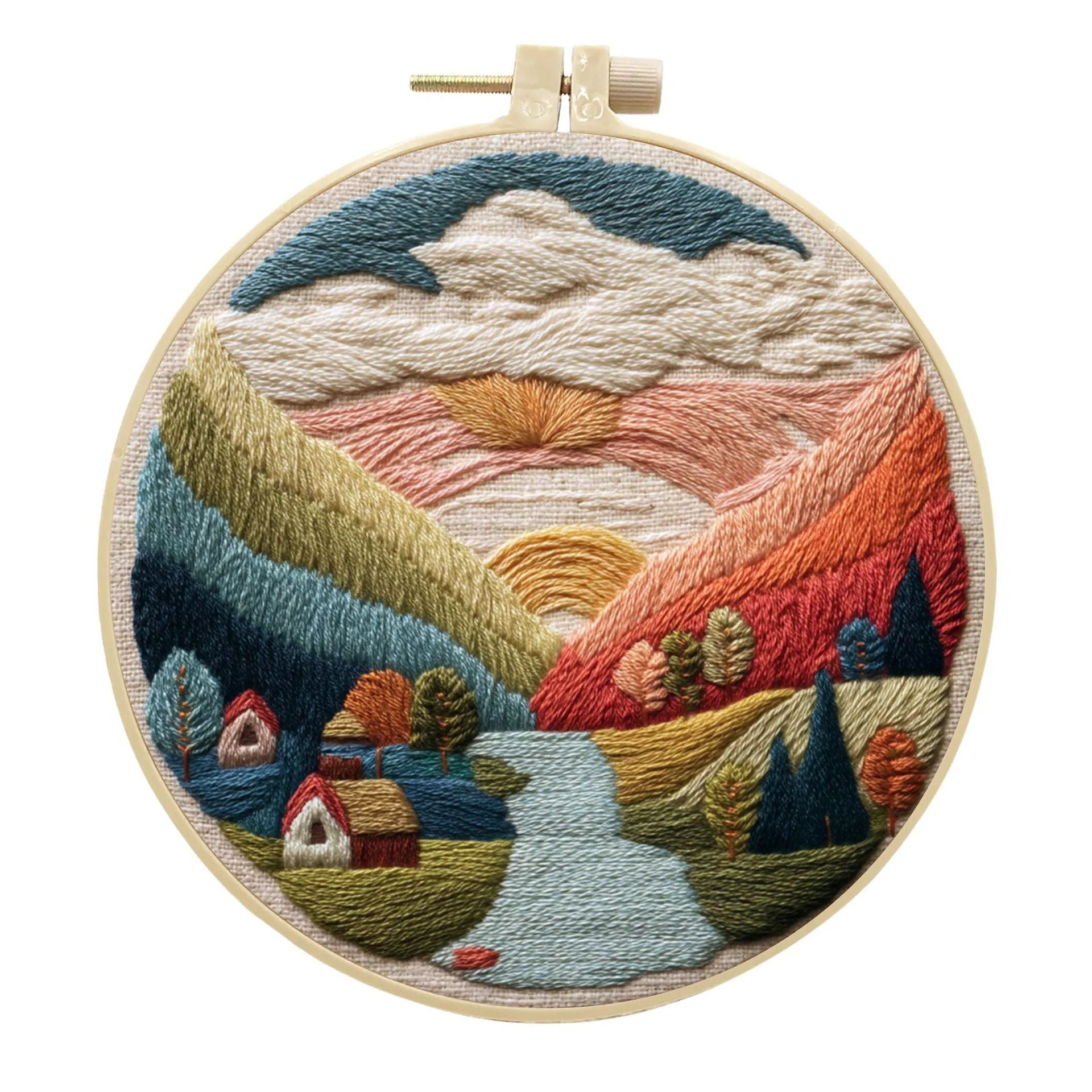 Embroidery DIY kit components: printed landscape fabric, embroidery hoop, coloured threads, and needles laid flat.