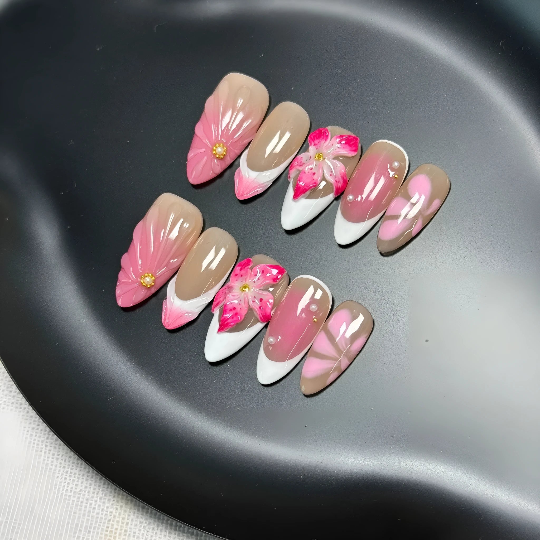 Set of white plastic almond-shaped nail tips with 3D raised lily and ice flower French manicure design.