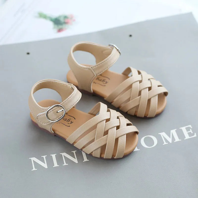 Kids buckle-toe soft sole woven sandals in white, black, and pink on a light background
