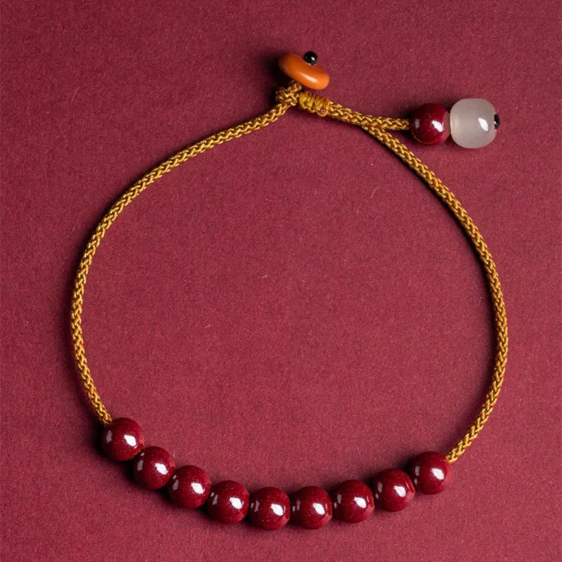 Hand-woven cinnabar and Hetian jade geometric bracelet on wrist showing natural stone textures