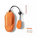Suede car key cover in cement grey, dark green, light grey, and orange colour options on a plain background.