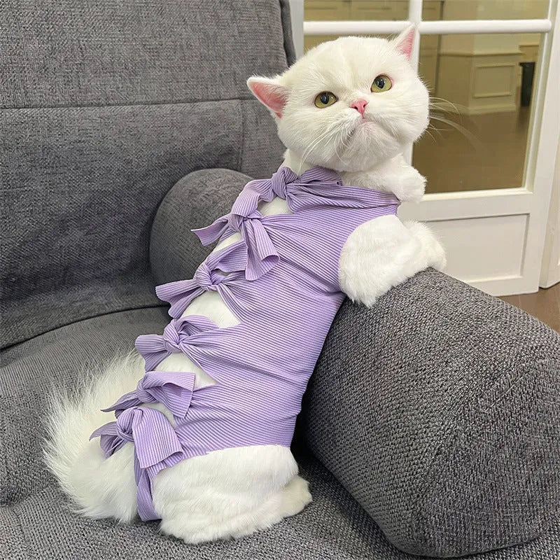 Pink lace-up cat recovery bodysuit on a table, showing back ties and full-body design for post-surgery care.