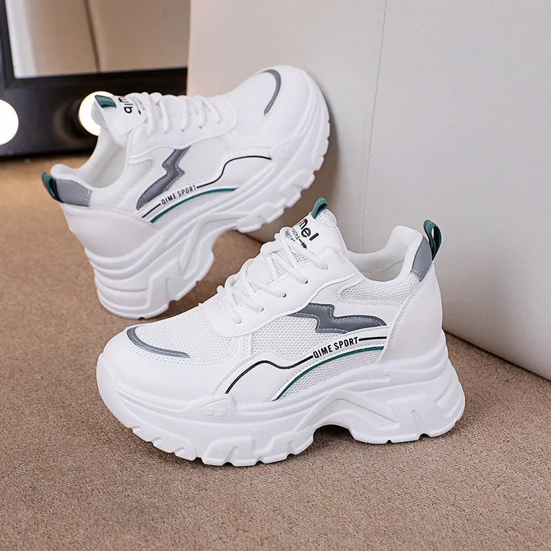 Women's white low-top sports trainers with cross shoulder straps and a lace-up front on a solid background.