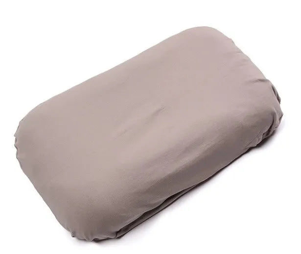 Beige portable baby nest cot crib for infants on a neutral background