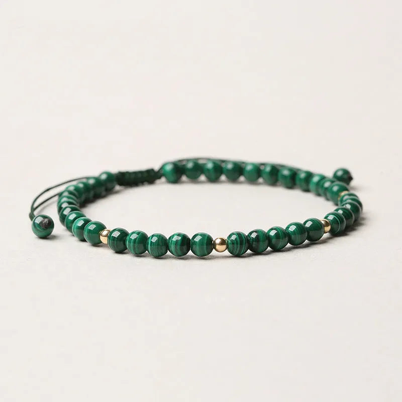 Natural green malachite crystal bracelet with golden balls on a woven hand strap.