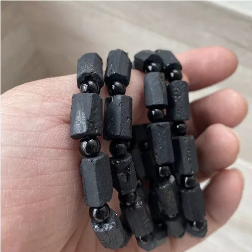 Black tourmaline rough stone bracelet on a wrist, showing natural texture and 10mm size