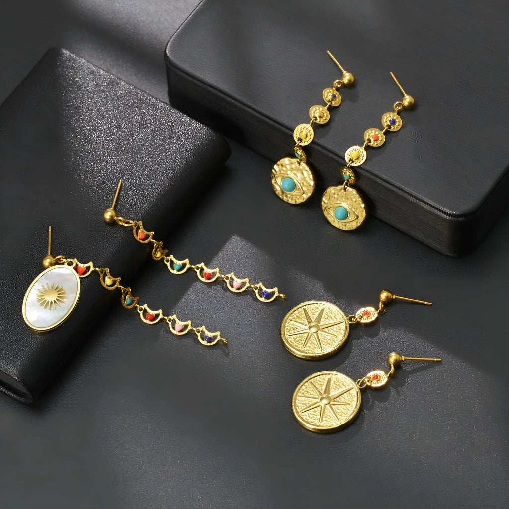 Set of three geometric earring pairs: stainless steel star, eye, and shell sun designs.