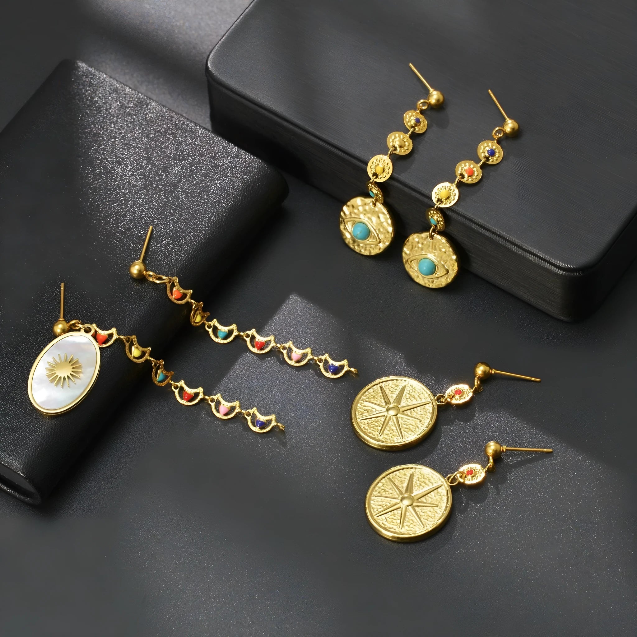 Set of three geometric earring pairs: stainless steel star, eye, and shell sun designs.