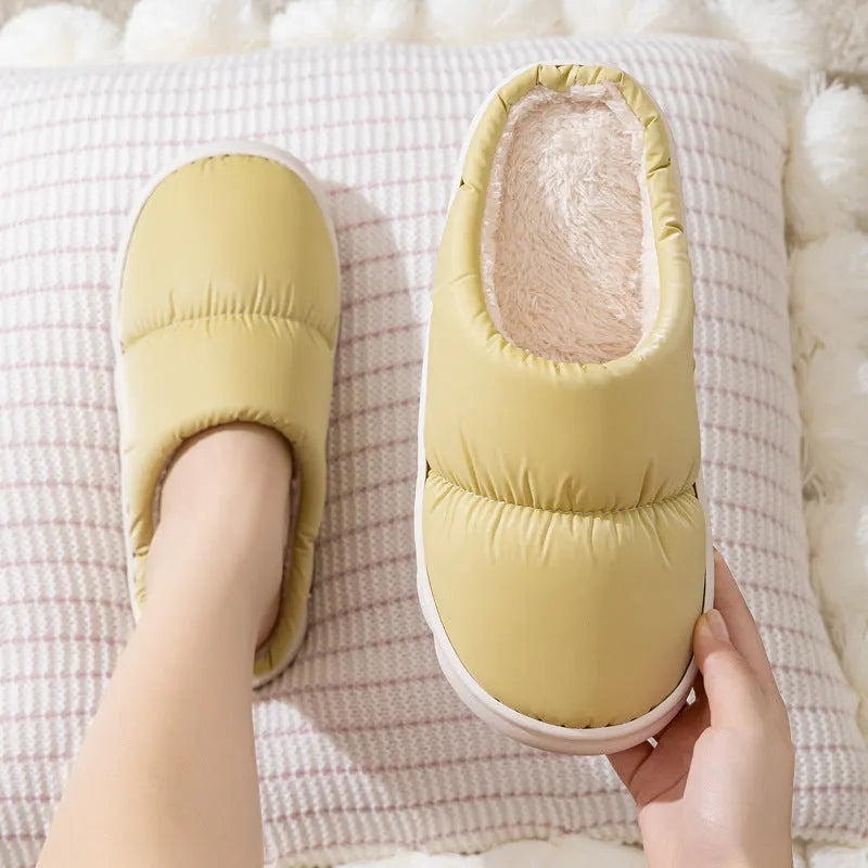 Blue down cotton winter slippers with a thick rubber sole and plush lining, shown on a wooden floor.