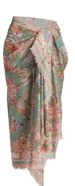 Women's creamy-white floral bikini swimsuit set with matching skirt on a beach background.