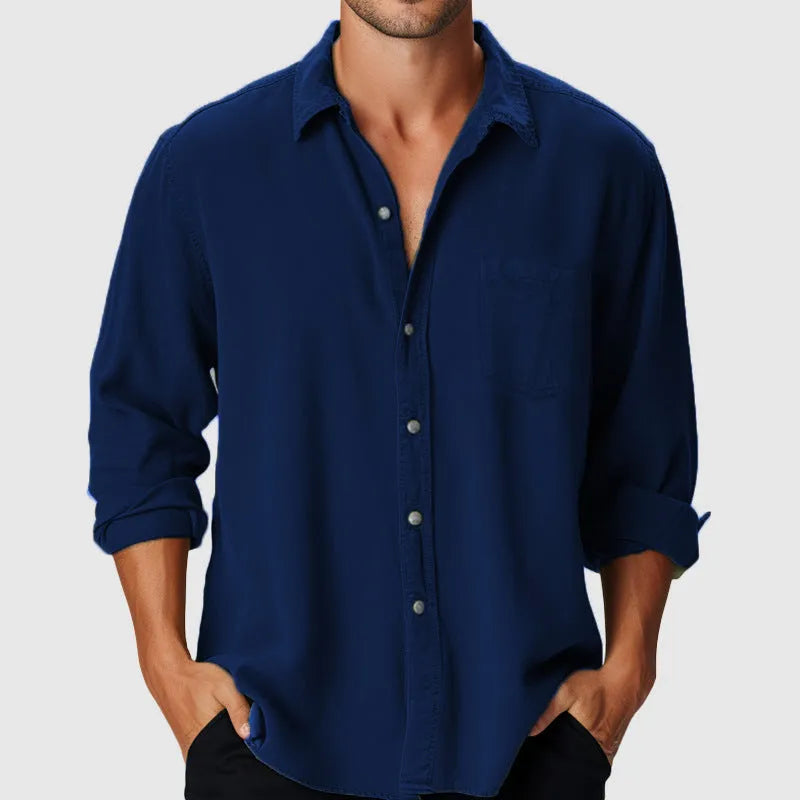 Man wearing a loose fit long sleeve shirt with a stand collar on a beach.