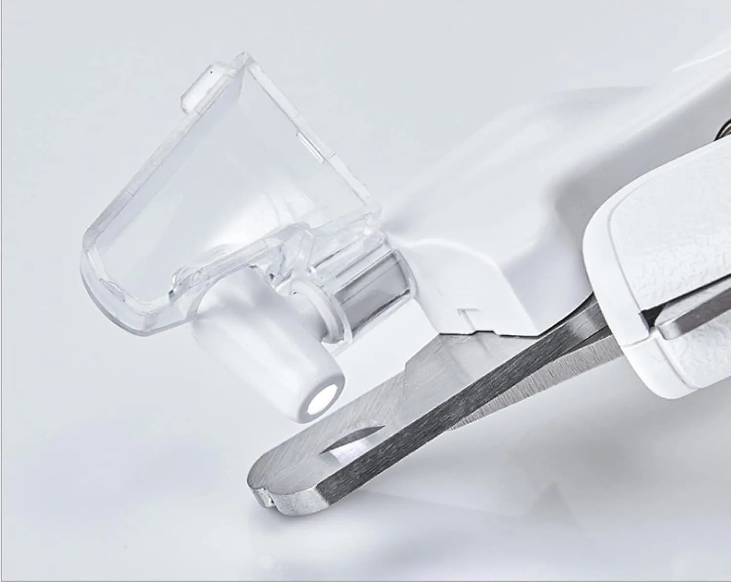 White pet nail clippers with LED light and transparent anti-splash guard next to a nail file on a table