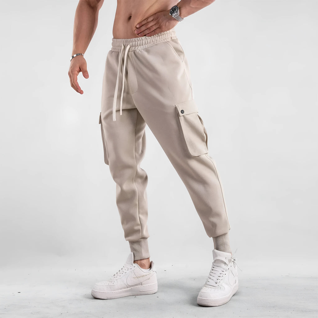 Men's loose-fit apricot coloured cotton sports trousers with an ankle tie and side pockets on a neutral background.