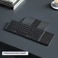 Black folding Bluetooth keyboard showing compact folded size beside mobile phone