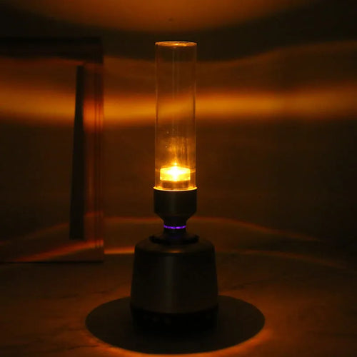 White silver cylindrical candlelight Bluetooth speaker and night light unit on a table