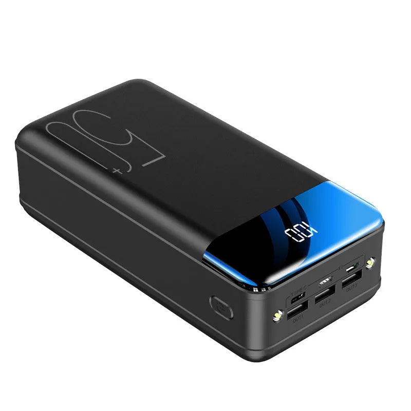 Black and white large 50000mAh portable power bank with multiple USB ports, showing scale next to a smartphone.