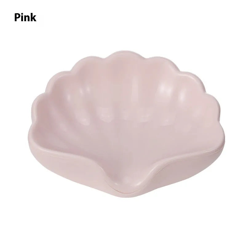 White or pink plastic shell-shaped soap dish for bathroom sink or shower.